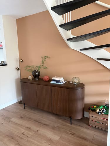 Klant's donkere by fonQ Grand dressoir staat in een stijlvol interieur onder een trap.