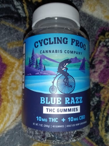 Reviewer's jar of Cycling Frog Blue Razz THC Gummies, showing the blue label and dark gummies inside.