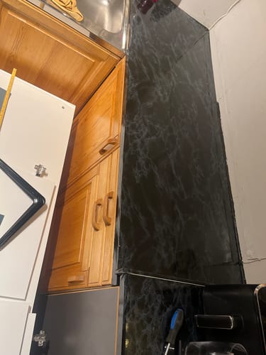 En anmelders kjøkkenbenk og vegg er dekket med den mørke, elegante kontaktplasten.