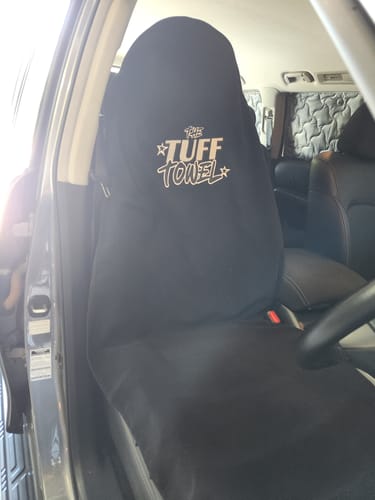 Customer's black Tuff Towel seat cover installed on a car's leather driver seat.