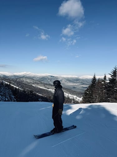 Reviewer standing on skis wearing the black baggy snow pants on a snowy mountain.