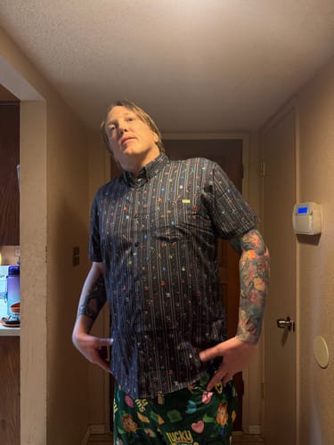 Reviewer showing the relaxed fit of the Mega Man 'Mega Pixels' shirt while wearing it with pajama pants in a hallway.