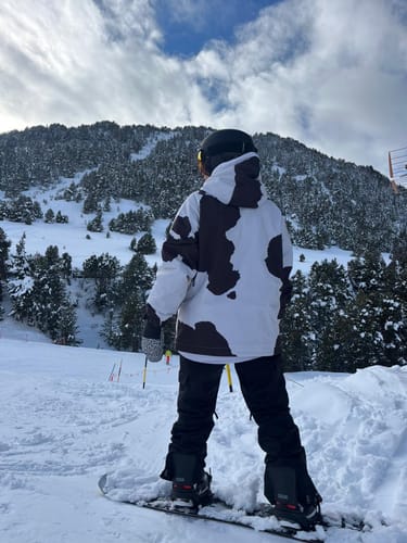 Customer on a snowy slope, seen from behind wearing the cow print snow jacket.