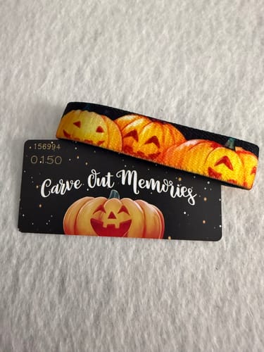Customer's Carve Out Memories Bracelet with an orange pumpkin design, shown with its black backing card.