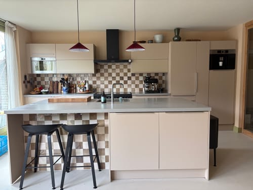 Recensent's twee rode HAY Matin hanglampen die boven een modern kookeiland hangen.