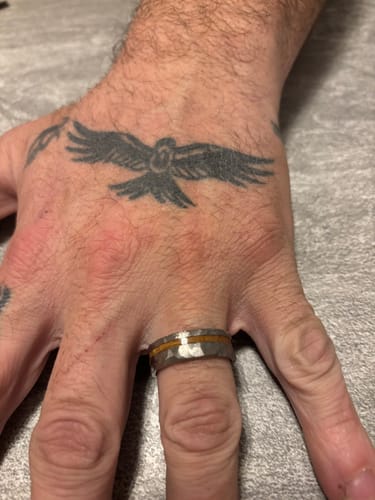 Close-up of a customer's hand wearing the hammered Lionheart ring, showing the wood inlay.