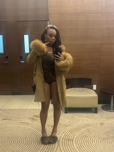 Reviewer taking a selfie in a brown Vice Body bodysuit, worn with a tan coat.