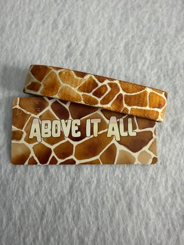Reviewer's Above It All Bracelet with a giraffe pattern, displayed with its matching collector's card.