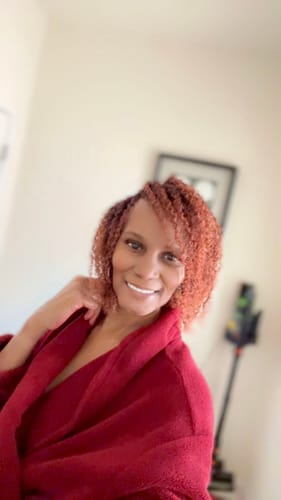 Reviewer in a robe showing her defined, reddish curls after using the Wash and Go Bundle.