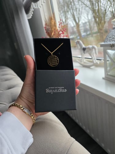 Customer holding an open black jewelry box showing the gold Family Tree Name Necklace inside.