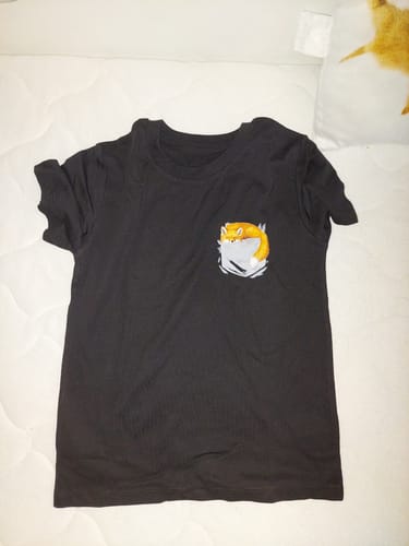 Ein Kunde zeigt das schwarze Fuchs Tasche Bio-Kindershirt, das flach auf einer Steppdecke liegt.