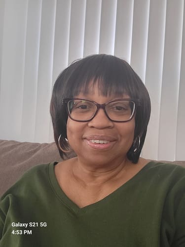 Customer wearing the dark, straight Motown Tress On The Go Full Wig while sitting on a couch.
