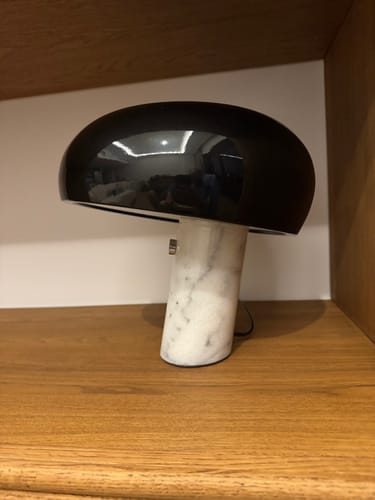 Customer's Marble Table Lamp with a shiny black shade and solid white marble base, placed on a wooden shelf.