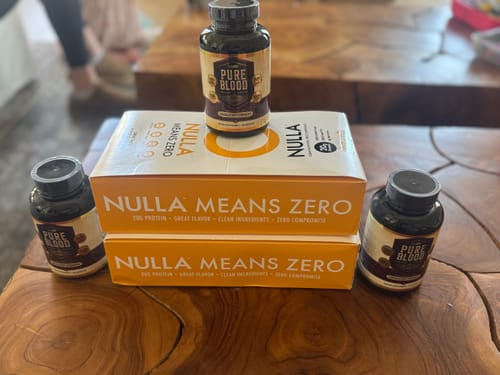 Customer's two boxes of Cleanform Nulla Protein Bars stacked on a wooden table with other supplements.