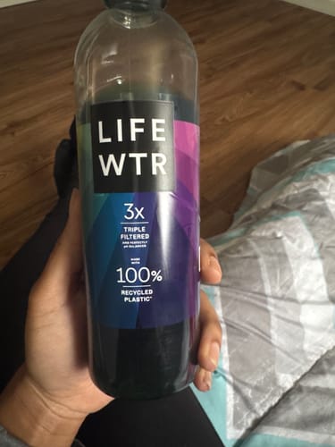 Reviewer holds a bottle of water mixed with the dark Body Magic Chlorophyll.