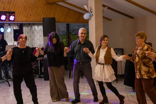 O clientă dansează într-o horă, purtând setul Maia maro, format din rochie albă și vestă.