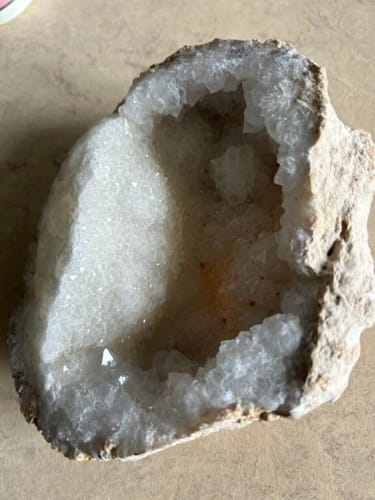 La géode de quartz d'une cliente, posée ouverte sur une surface pour montrer l'intérieur rempli de cristaux blancs.