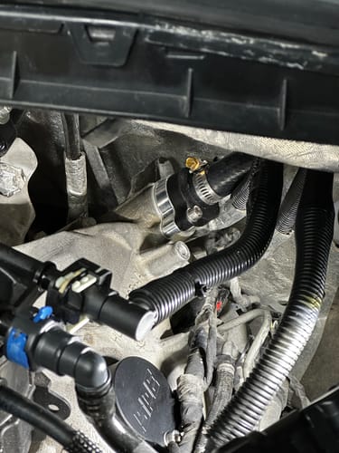 Reviewer's close-up view of the installed SPE Motorsport CCV Reroute Kit connected to a hose in an engine.