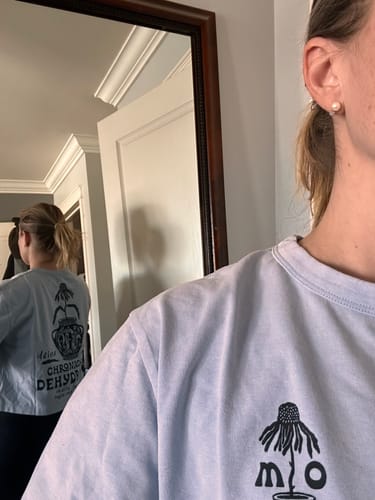 Close-up of a reviewer showing the front and back graphics of the Chronically Dehydrated T-Shirt in a mirror.