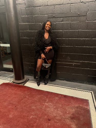 Reviewer posing in the black Faux Fur Plush Long Coat, worn over a dress and boots.