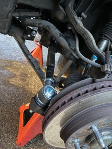 Close-up of a customer's new black Heavy Duty Tie Rod installed on the front suspension of a vehicle.