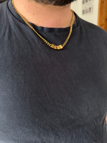Reviewer wearing the gold-colored Legacy necklace with four square beads against a dark t-shirt.
