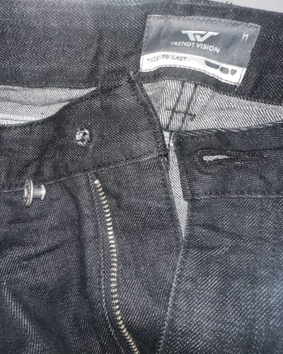 Reviewer showing a close-up of the black Raw Denim Jeans with a broken clip button.