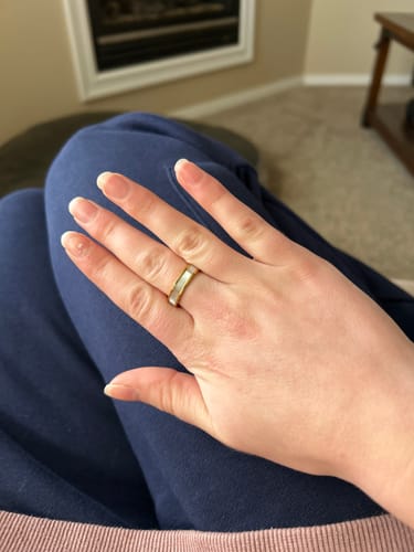 Customer's hand resting on their lap, wearing the Ivory Pearl Gold Ring in a casual setting.