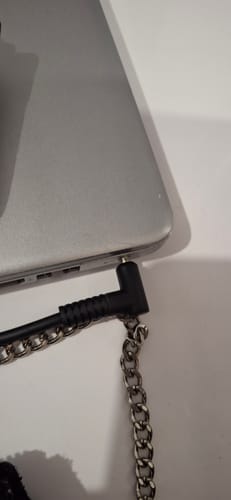 Vue rapprochée du connecteur d'alimentation du client, branché sur un ordinateur portable argenté.
