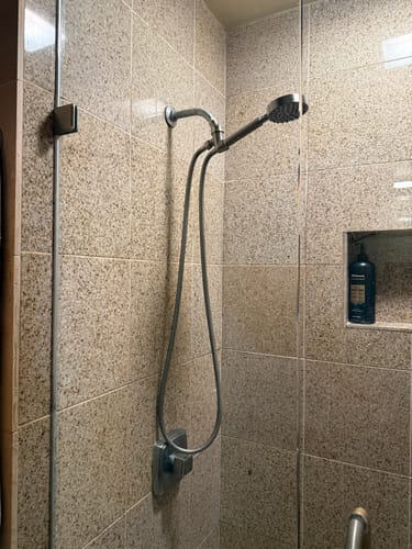 Customer's Handheld Shower Head installed in a modern tiled shower with the flexible hose hanging down.