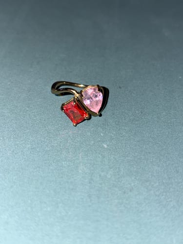 A customer's Navae Birthstone Ring with a pink pear-cut stone and a red radiant-cut stone on a gold band.