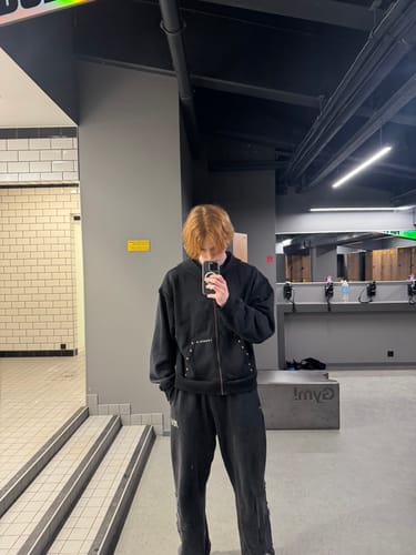 Customer wearing the black Deconstructed Terry Hoodie and matching pants, showing the boxy fit and studded pockets.