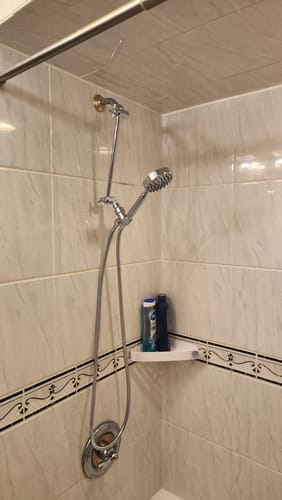 Customer's handheld shower head set installed with an adjustable extension pipe in a tiled shower.