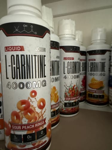 Customer's collection of Liquid L-Carnitine 4000MG bottles on a shelf, showing Sour Peach Rings and other flavors.