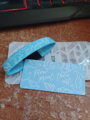 Customer's 'How Great Thou Art' bracelet in light blue with a dove pattern, displayed next to its matching card.
