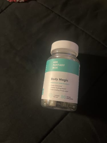 A customer's bottle of Body Magic Chlorophyll Pills resting on a dark, rumpled fabric surface.