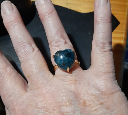 Cliente portant la Bague Apatite, avec sa pierre bleue en forme de cœur et une monture dorée.
