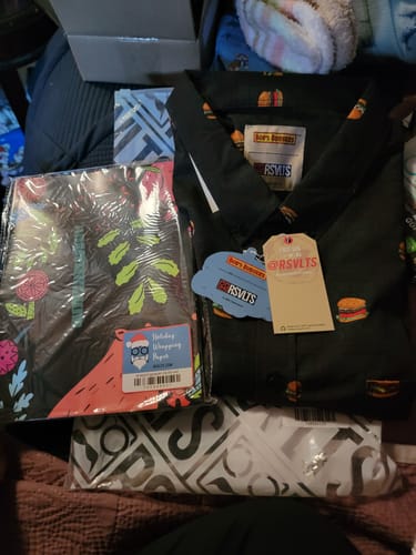 Reviewer's folded black Bob's Burgers shirt with tags, shown with a package of free wrapping paper.