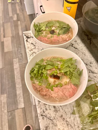 Customer's two bowls of homemade pho prepared with tender Halal Beef Hot Pot Slices and fresh herbs.