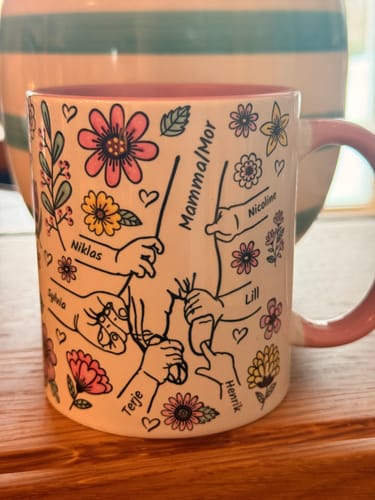 Närbild på kundens personliga Kärleksmugg med ett tryck av händer, namn och färgglada blommor.