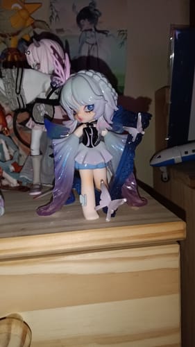 Customer's NONO SOVA Nightmare Lullaby figurine with white hair and a blue cape, displayed on a wooden dresser.