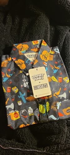 Customer's Looney Tunes "The ACME Catalog" shirt folded on a fuzzy black surface, showing the colorful all-over print and tag.
