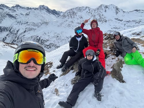 Customer wearing the black retro track snow jacket with friends on a snowy mountain.