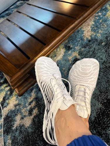 Customer wearing white Lorax Pro barefoot shoes indoors, showing the wide toe box.