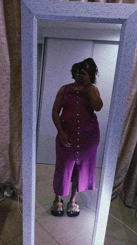 Reviewer taking a mirror selfie in the purple sleeveless button-down knitted dress.