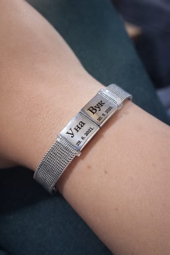 Customer wearing the silver-colored Lux mesh bracelet with two personalized engraved pendants on their wrist.