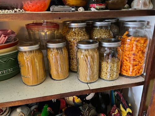 Customer's organized pantry shelf with various mason jars of pasta and snacks sealed with the Mason Genie kit.
