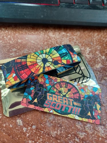 Customer's 'Great Scott' Goldie Mystery ZOX wristband and card with a colorful stained-glass design on a desk.