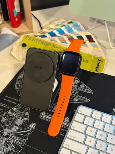 Reviewer's black 3-in-1 Foldable Charging Stand MAG lying flat on a desk next to an Apple Watch.