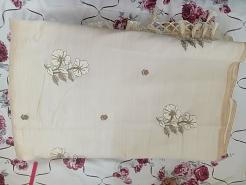 Customer's folded cream saree, showing the golden floral embroidery and fringed edge.